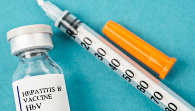 A healthcare professional holding a syringe with the Hepatitis vaccine, symbolizing preventive care for global patients.